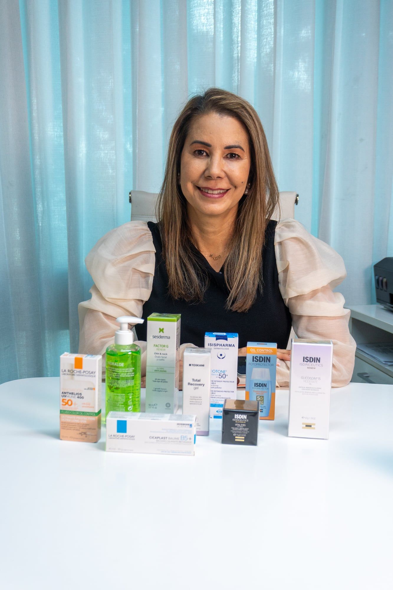 Foto final: la doctora en su consultorio junto a productos para el cuidado de la piel