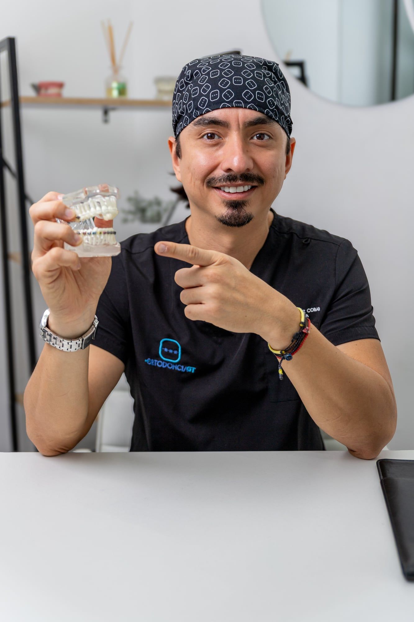 Ortodoncista señalando un modelo dental desde su escritorio