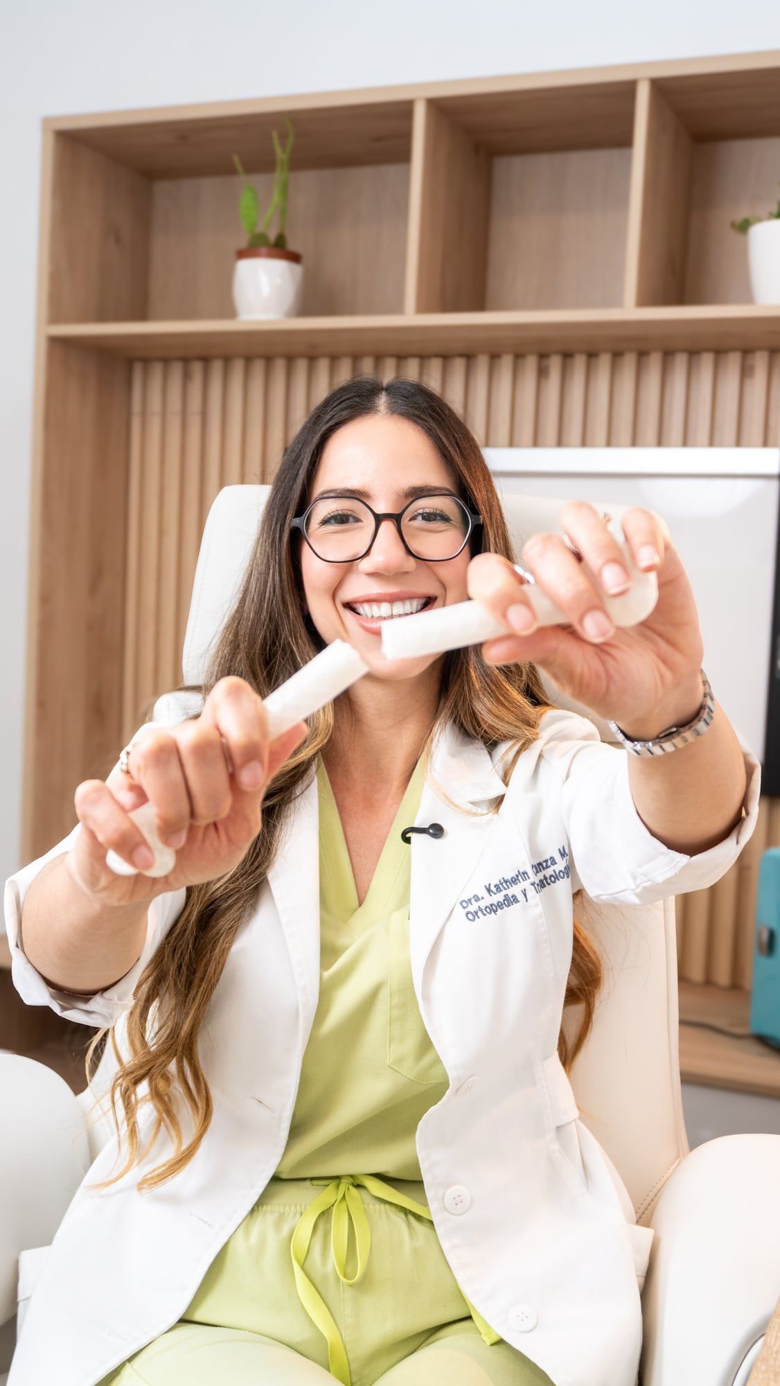 Doctora ortopedista sonriendo mientras muestra un modelo de hueso